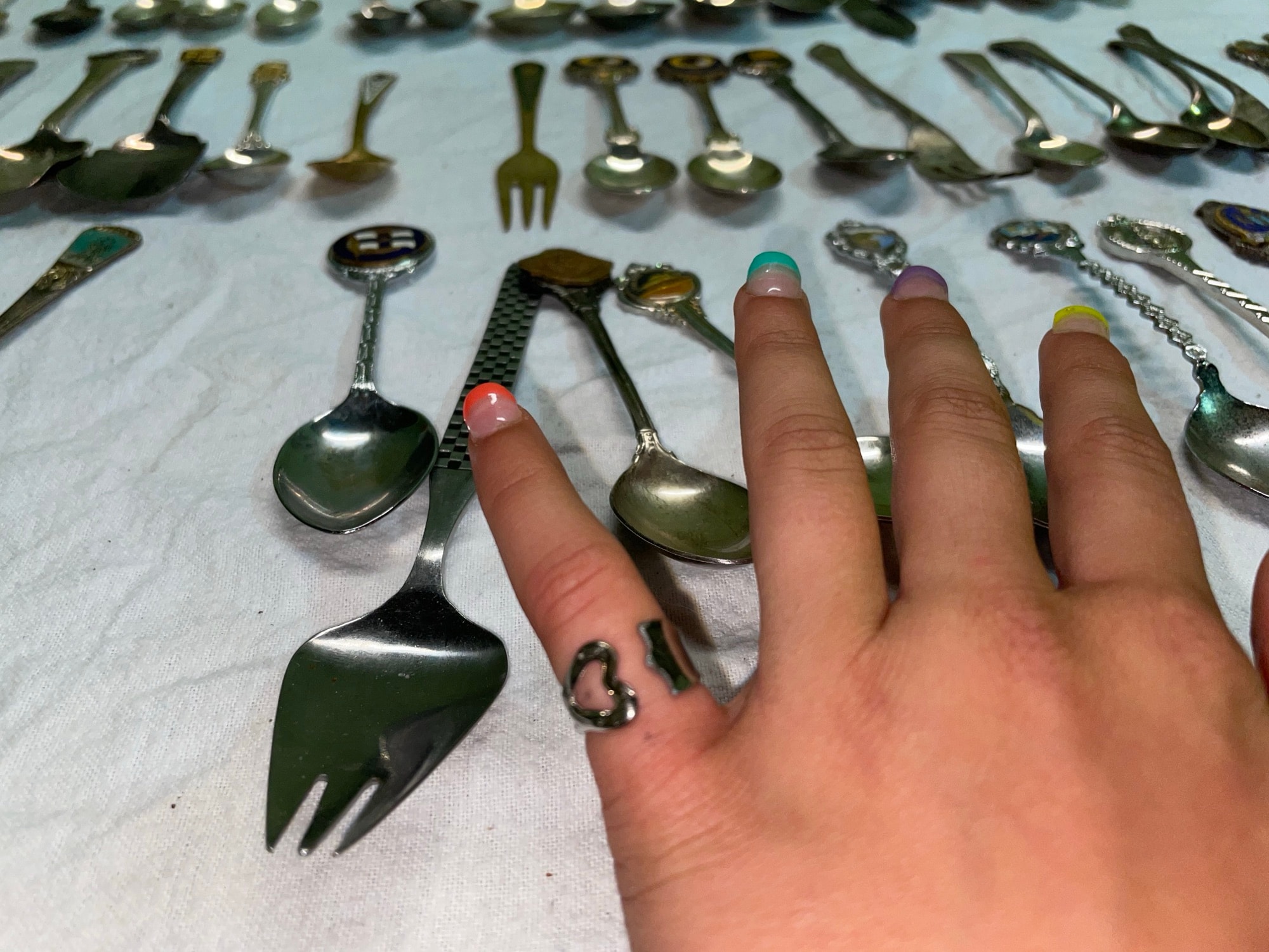 Old silver spoons and forks laid out on a cloth.